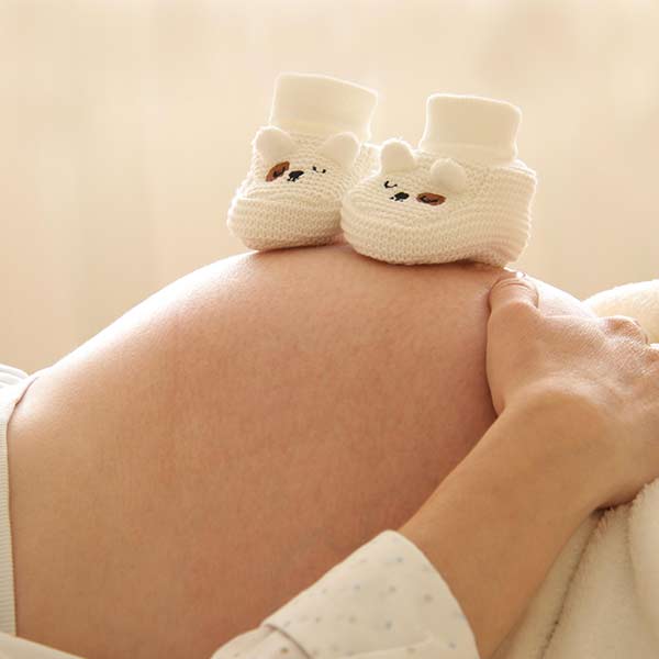 Osteopathische Behandlung am Bauch einer schwangeren Frau